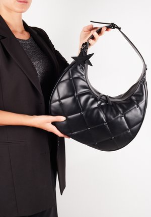 Sort quilted læderhåndtaske med en halvmåneform, prydet med metalnagler og et stjernesymbol. Har en enkelt skulderrem.
