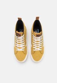 Sneaker alte in suede giallo con lacci bianchi, dotate di un'etichetta in pelle color miele, suola in gomma e strisce laterali a contrasto.