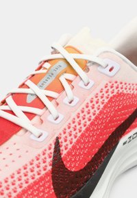 Αθλητικά παπούτσια τρεξίματος Nike Pegasus με δίχτυ σε κλίμακα ροζ προς κόκκινο, λευκά κορδόνια και μαύρο λογότυπο swoosh. Σημειωτήρα η επενδεδυμένη γλώσσα.