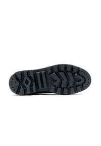 Suela de zapatilla de goma negra con surcos profundos, que presenta patrones distintivos, elementos de tracción y agujeros de drenaje para mejorar el agarre y la comodidad.