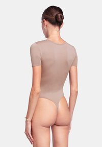 Body light brown a maniche corte, texture liscia e design con schiena a perizoma. Silhouette aderente, senza hardware o motivi visibili.