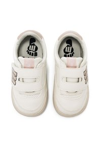Zapatillas de cuero blancas con correas de velcro, acentos beige, punta redondeada y un gráfico negro en la plantilla.