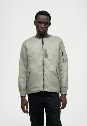 Jaqueta bomber acolchoada cinza claro com decote redondo, fecho frontal em zíper, bolsos laterais e um bolso em zíper no braço esquerdo. Textura suave.