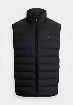 Svart puffervest med høy krage, horisontal quilt, glidelås foran og en liten logo på brystet. Glatt tekstur.