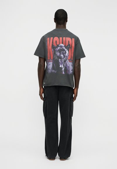 Γραφικό κοντομάνικο t-shirt σε σκούρο γκρι με μεγάλο σχέδιο πάνθηρα στην πλάτη. Συνδυασμένο με μαύρο παντελόνι cargo με φαρδιά μπατζάκια και πλαϊνές τσέπες.