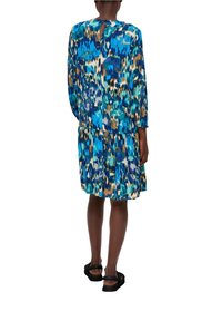 Blau gemustertes Kleid mit gestuftem Saum und langen Ärmeln. Details mit Schlitz im Rücken. Tragen mit schwarzen Sandalen. Glatte Stoffstruktur.