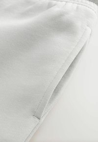 Szürke sportshort, textúrált anyagból, oldalsó zsebekkel és elasztikus derékrésszel. Minimalista dizájn sima felülettel.