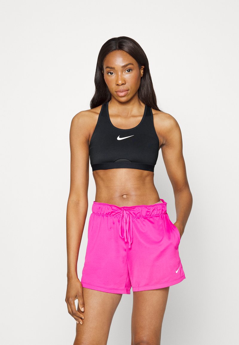 Μαύρος αθλητικός στηθόδεσμος και ροζ σορτσάκι κατασκευασμένα από λείο, ελαφρύ ύφασμα. Ο αθλητικός στηθόδεσμος διαθέτει λευκό λογότυπο, ενώ το σορτσάκι έχει ελαστική μέση.