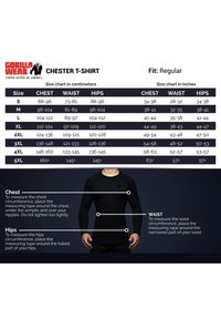Matenoverzicht voor het Chester T-shirt van Gorilla Wear, met afmetingen in centimeters en inches voor borst, taille en heupen. Zwarte achtergrond.