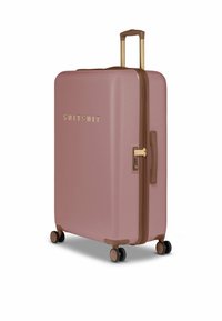 Harde koffer in gedempt roze met een gladde textuur, gouden hardware, bruine accenten en vier wielen voor mobiliteit. Ritsluiting inbegrepen.