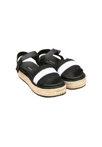 Sandalias en blanco y negro con tiras elásticas, plataformas de yute trenzado y acentos textiles en forma de ondas. Suela negra suave con forma redondeada.