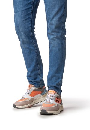 Mehrfarbige Turnschuhe mit grauem, orangefarbenem und weißem Design; Obermaterial aus Mesh, dicke Sohle mit gesprenkelter Textur und kontrastierende Schnürsenkel.