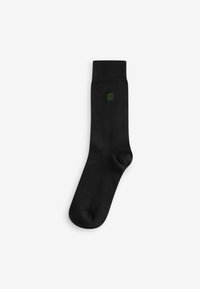Black cotton sock with a soft texture, featuring a ribbed cuff and a small green logo accent near the ankle. Standard crew length design.