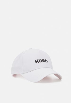 White baseball cap with curved brim and black "HUGO" text embroidered on the front center.