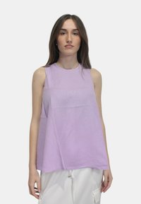 Top senza maniche di colore lavanda con scollatura rotonda, vestibilità comoda e texture liscia. Abbinato a pantaloni bianchi larghi.