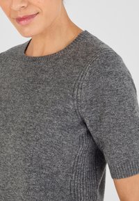 Maglione grigio a maglia con maniche corte, scollo rotondo, dettagli a coste sulle spalle e un tessuto morbido e texturizzato.