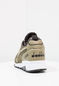 Oliwkowe trampki wykonane z zamszu i siateczki, z białą podeszwą, fakturowanymi akcentami oraz logo "diadora" na pięcie.
