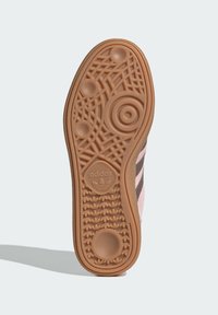 Sola em borracha com um padrão texturizado, apresentando designs circulares e lineares. Cor castanho claro com um logótipo e nome da marca em relevo.