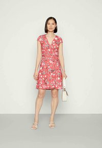 Vestido envolvente floral em coral com mangas curtas, decote em V e cintura com laço. Apresenta uma saia rodada e detalhes em padrão floral branco.