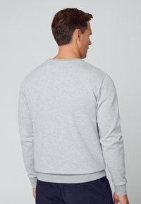 Grauer Sweatshirt aus weichem Material, mit rundem Halsausschnitt und langen Ärmeln. Rippenbündchen an den Ärmeln und am Saum, einfarbig ohne sichtbare Muster.
