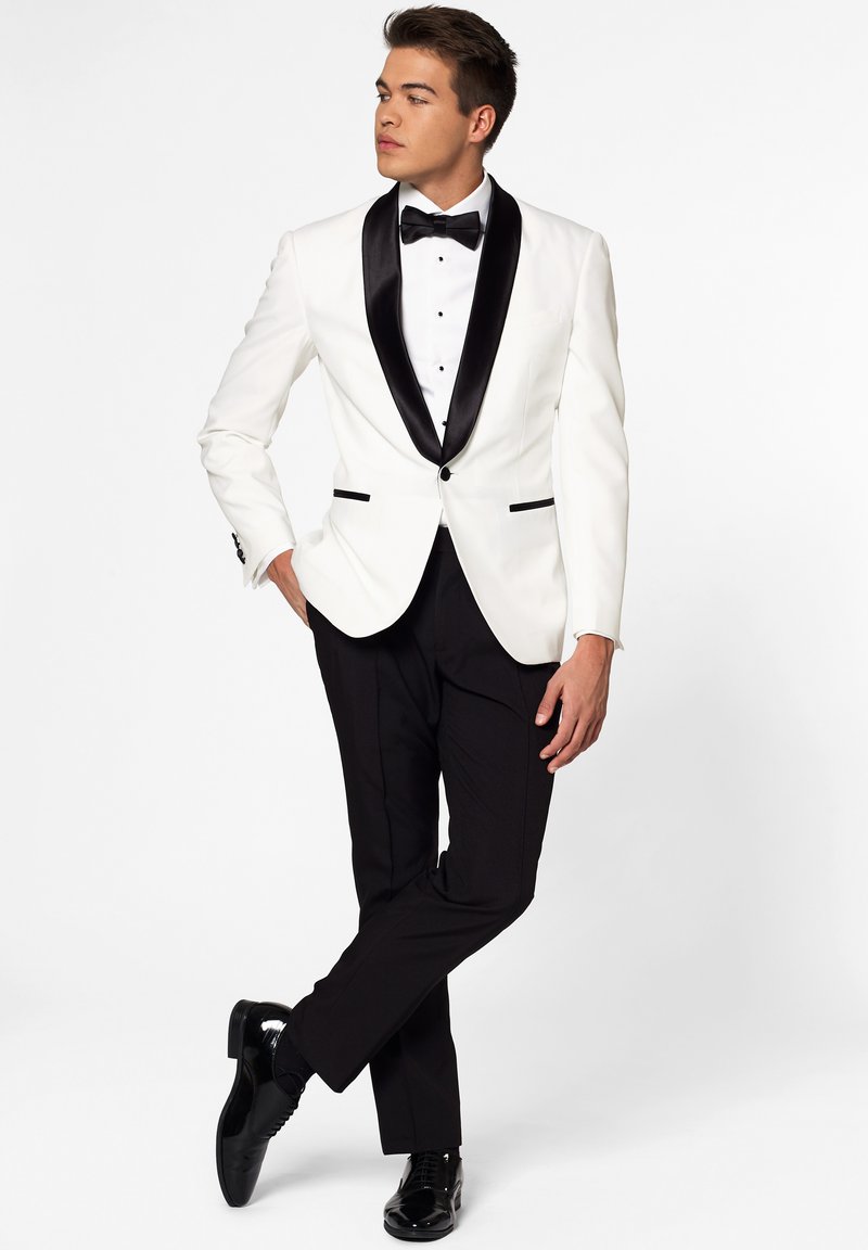 White tuxedo jacket with black satin lapels, black bow tie, and slim-fit black trousers. Glossy black shoes complete the formal attire.