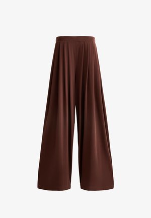 Hlače širokega kroja iz bogate rjave tkanine, z visokim elastičnim pasom in mehko teksturo, zasnovane z naborki za pretok in gibanje.