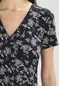 Svart blommig omlotklänning med korta ärmar, med en strukturmönster, blå och röda blommiga tryck, och scalloped halsringning.