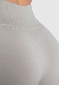 Helles graues, tailliertes Sportoberteil mit hohem Kragen. Der Stoff hat eine glatte, elastische Textur und subtile gerippte Details.