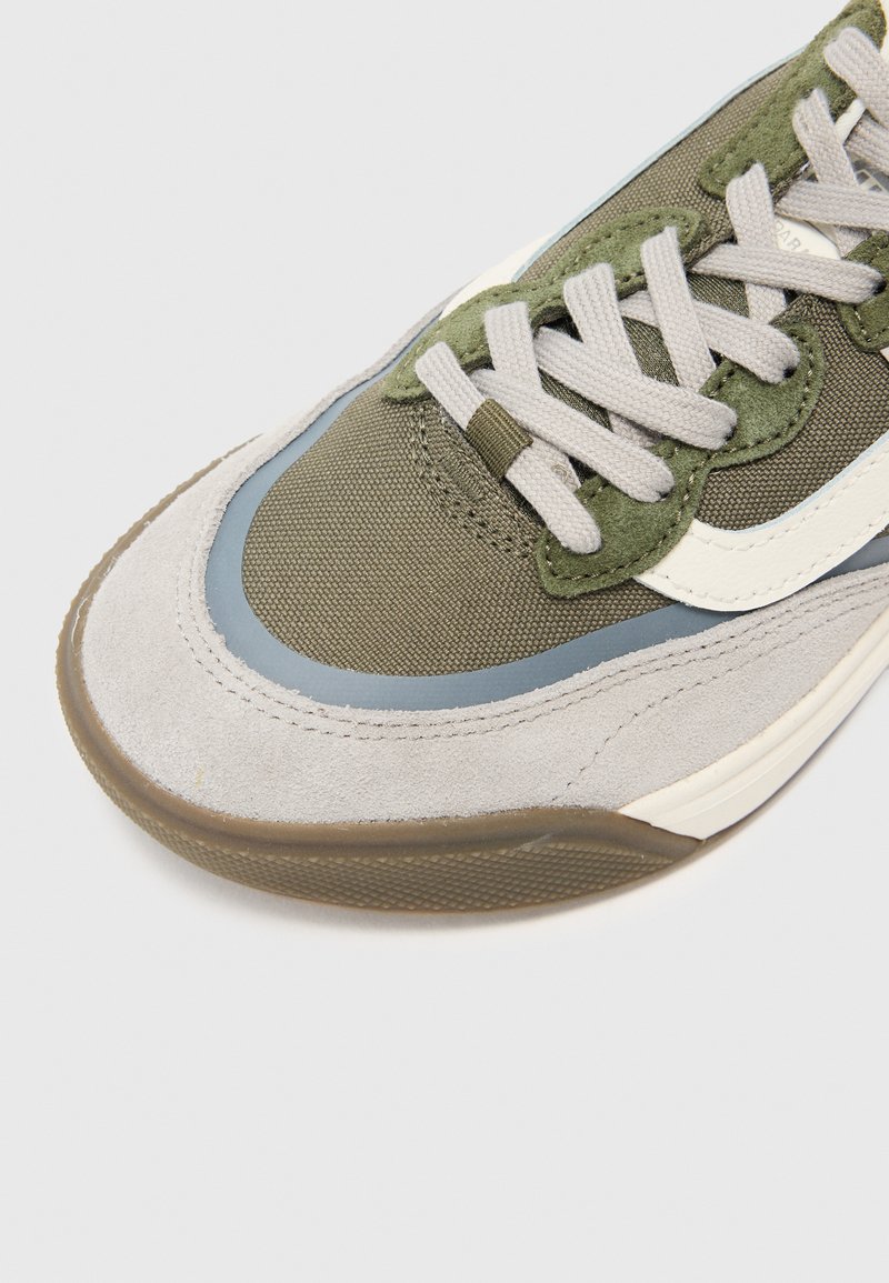 Groene en grijze sneaker met een bovenwerk van suede en mesh, grijze veters en een rubberen zool. Heeft een blauwe accent en een witte logo-detail.