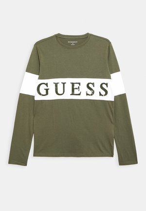 Olijfgroene lange mouw t-shirt met een witte streep waarop het woord "GUESS" staat in dikke, donkergroene letters over de borst. Gemaakt van katoen.