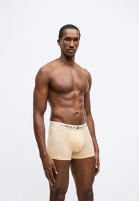 Μπεζ μποξεράκια από την Tommy Hilfiger με ζωνάρι μέσης με αντίθετο λογότυπο. Μαλακό ύφασμα, εφαρμοστή σχεδίαση και μήκος μέχρι το μέσο του μηρού.