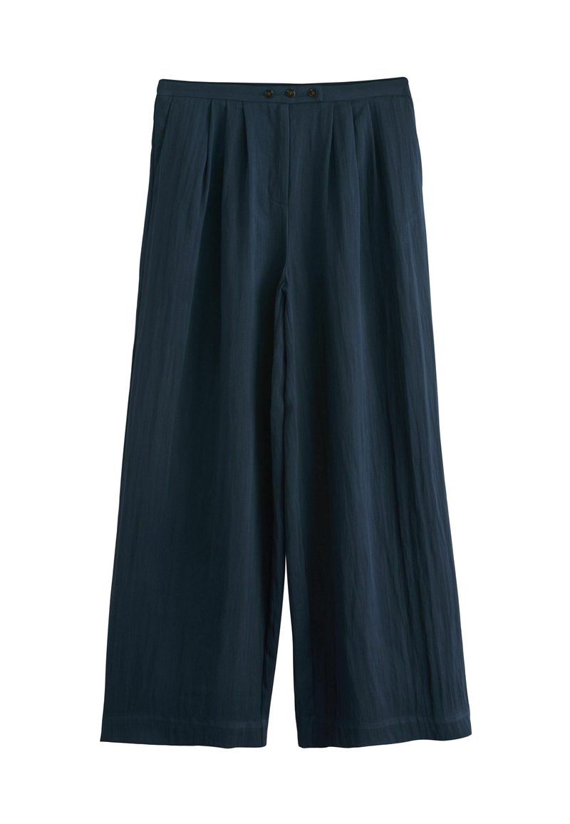 Plati gaisie bikses tumši jūrā zila tonī, izgatavotas no viegla auduma. Iekļauj plisētu priekšpusi, divas pogas jostasvietā un gludu tekstūru.