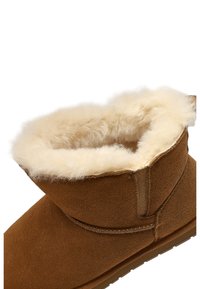 Braune Wildleder-Ankle-Boots mit einem weichen, cremefarbenen Kunstfellfutter, abgerundeter Spitze und flacher Gummisohle. Mit gesticktem Nahtdetail.