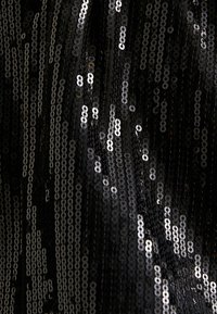 Tissu noir recouvert de paillettes brillantes, présentant un mélange de formes circulaires et de tailles variées, créant une surface réfléchissante et texturée.