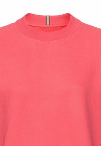 Korallefarbenes Sweatshirt mit geripptem Rundhalsausschnitt, das ein schlichtes Design und eine subtile Textur aufweist. Es hat einen vertikalen grauen Streifen am hinteren Hals.