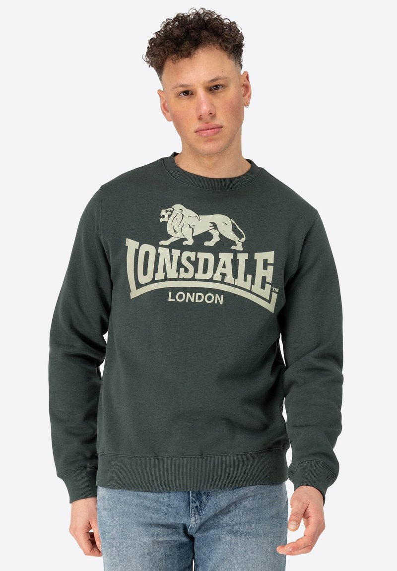 Sötétzöld pulóver, puha anyagból, világos színű oroszlán grafikával és a "Lonsdale London" felirattal. Kerek nyakú dizájn.