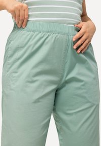 Ljusa gröna, elastiska midjebyxor i ett mjukt tyg, med sidofickor och en avslappnad passform, lämpliga för vardagsbruk.