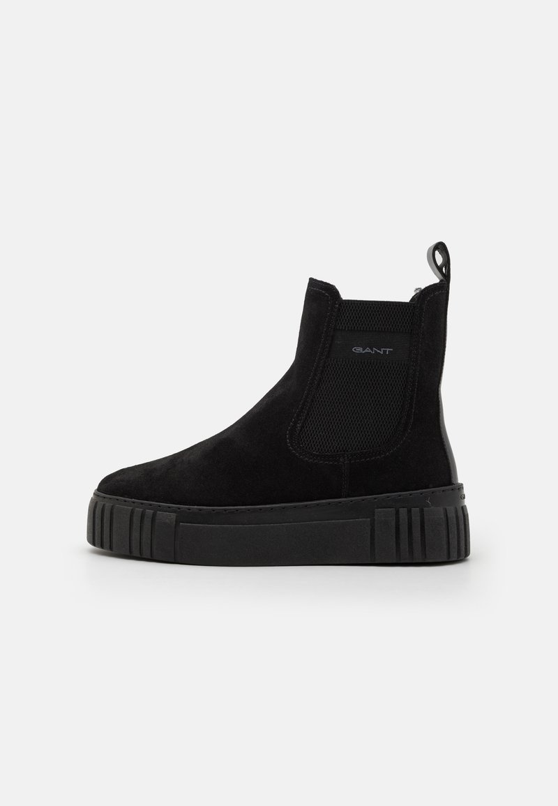 Black suede ankle boots with elastic side panels, rubber sole, and textured accents. Features a pull tab for easy wear.