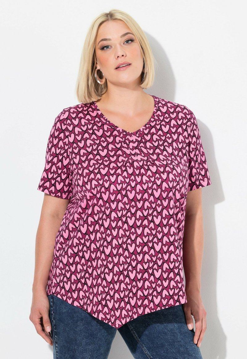 Korte mouwen T-shirt van roze stof met een hartpatroon in verschillende tinten roze. V-hals ontwerp met een licht gebogen zoom.