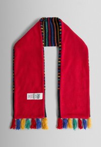 Rød fleecehalstørklæde med flerfarvet stribet foring, der har kvaster i blå, grøn, gul og rød i enderne. Etiket synlig nær bunden.