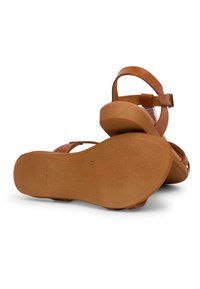 Brown sandals featuring an open-toe design, adjustable ankle strap, and textured rubber sole with a low heel.