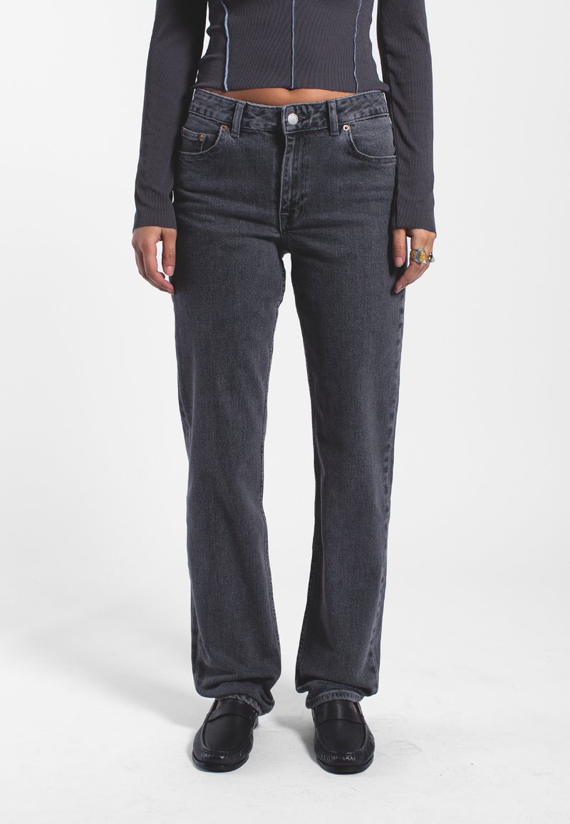 Jeans grigi a gamba dritta con design classico a cinque tasche, realizzati in denim, presentano una leggera texture lavata e accenti di cucitura arancione.