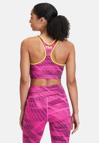 Rosa och grå mönstrad sportbh med racerback-design och ljusgula detaljer. Kombinerad med matchande högmidjade leggings.