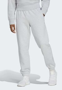 Harmaat verkkarit, jotka on valmistettu pehmeästä kankaasta, ja niissä on joustava vyötärö ja hihnat. Yhdistettyinä harmaisiin ja valkoisiin urheilukengiin, jotka sopivat yhteen.