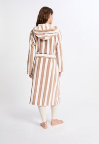 Accappatoio a righe in morbido poliestere, con cappuccio. I colori includono beige e bianco. Include una cintura coordinata e arriva a metà polpaccio.