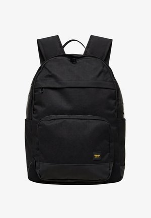 Zaino nero con spallacci imbottiti, tasca frontale con cerniera, tasche laterali e una piccola etichetta gialla e nera nell'angolo in basso a destra.