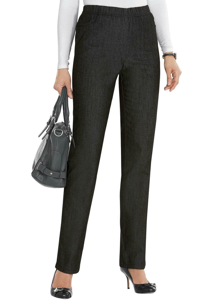 Zwarte rechte broek met een elastische tailleband, gemaakt van gladde stof, gecombineerd met een grijze handtas en zwarte lakleren hakken.