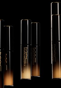 I prodotti MAC Studio Radiance in eleganti bottiglie nere e oro, con un design a gradiente dal scuro al chiaro, e una branding raffinata.