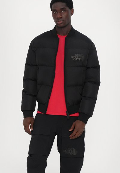Black puffer jacket with a zip front, ribbed cuffs, and hem. Worn over a red shirt, paired with black cargo pants featuring front pockets.