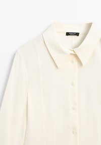 Camicia bianca sporca con colletto a punta e maniche lunghe, design minimalista, etichetta che riporta "Massimo Dutti."